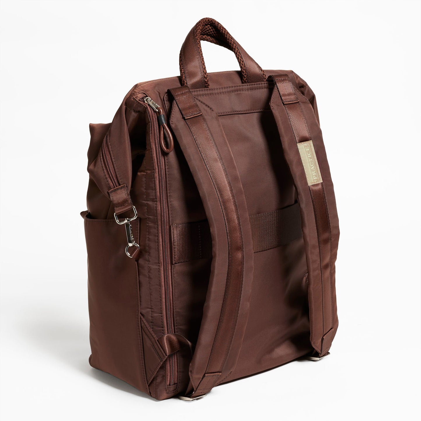 Back Facing view of the Karma Backpack in Mushroom Brown Nylon. Backpack has a top handle and a convertible strap to carry your backpack as a tote for easy grab and go! Back side has back zipper for easy access to your laptop, a trolley sleeve for easy travel on top of your luggage, and 2 comfy backpack shoulder straps