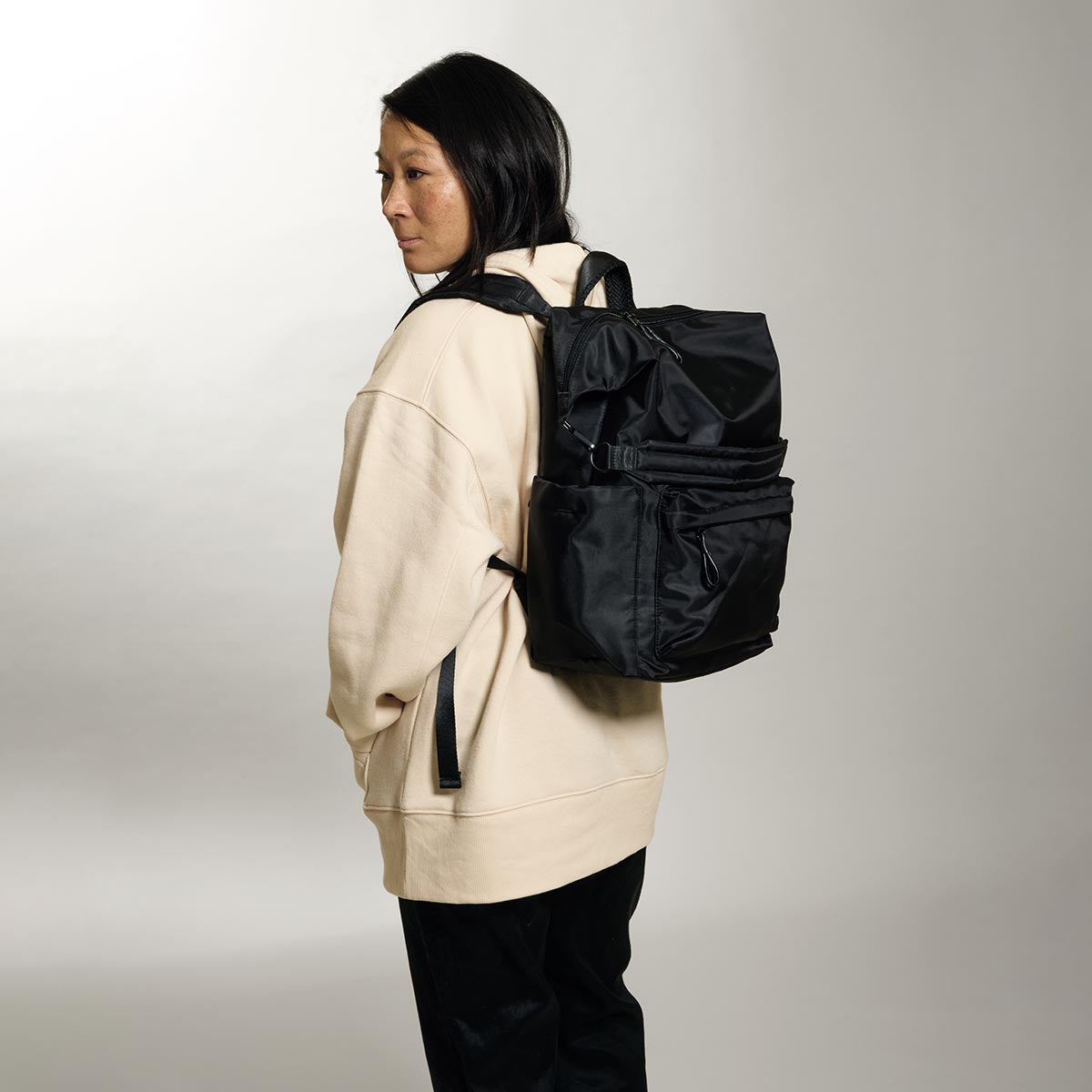 Practice Karma Medium Backpack in Eclipse black color on model in cream sweatshirt