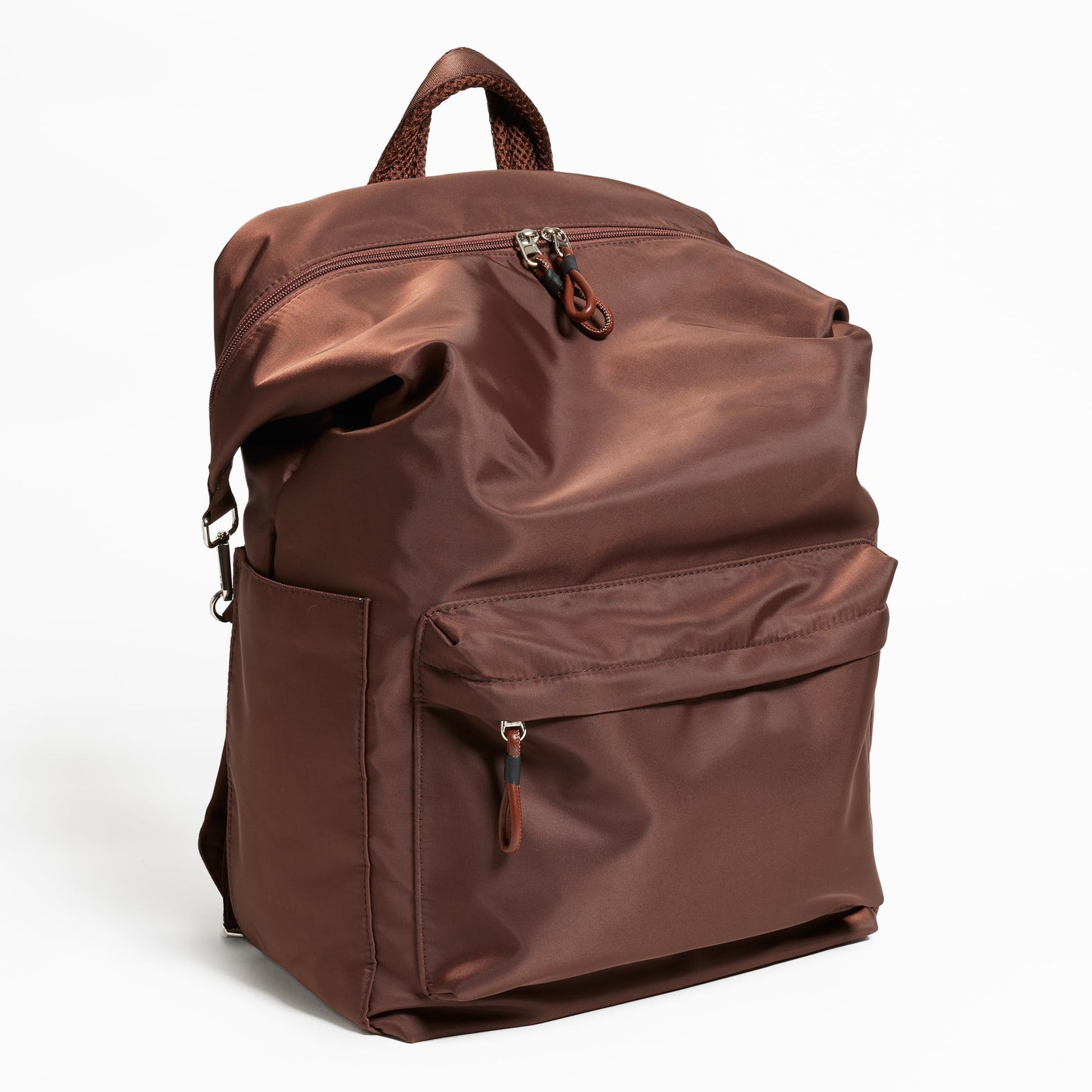 Angled Front Facing view of the Karma Backpack in Woodland Brown Nylon. Backpack has a top handle and a convertible strap to carry your backpack as a tote for easy grab and go! Front has a large pocket and both sides of backpack has 2 large pockets for your water bottle and other travel needs!