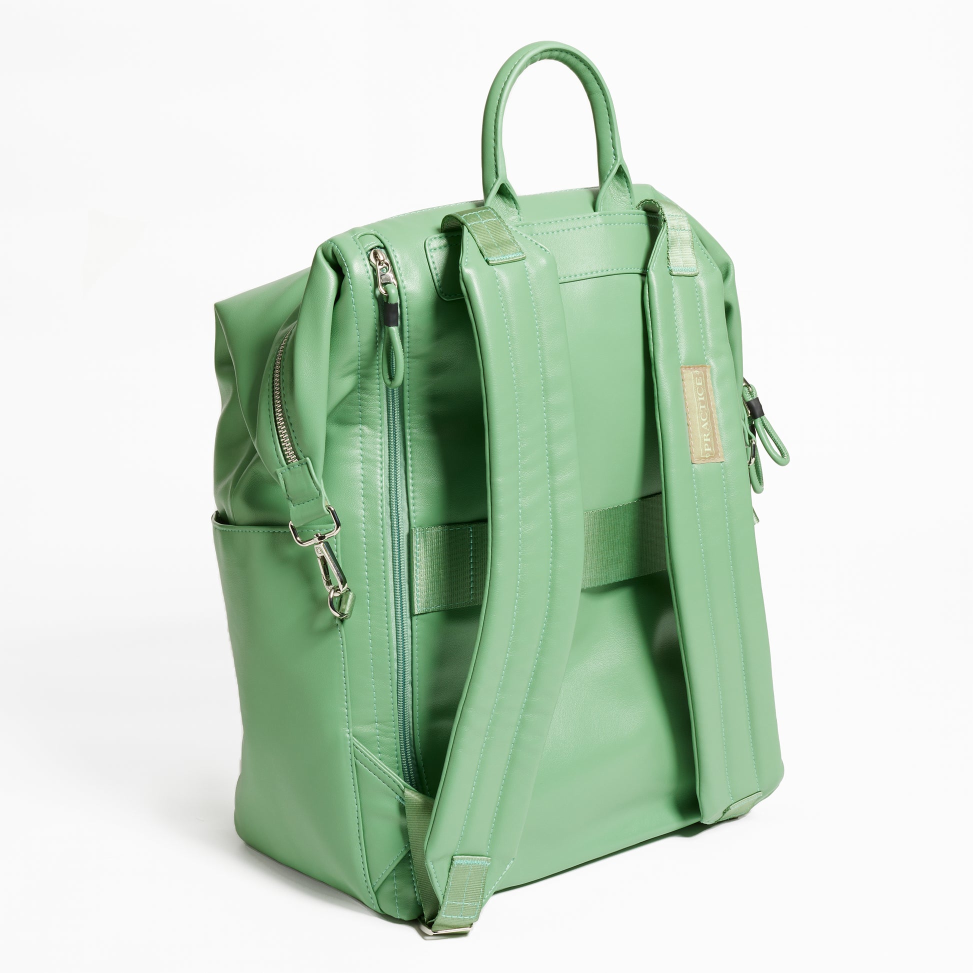 Back Facing view of the Karma Backpack in Aloe Green colored Vegan Leather. Backpack has a top handle and a convertible strap to carry your backpack as a tote for easy grab and go! Back side has back zipper for easy access to your laptop, a trolley sleeve for easy travel on top of your luggage, and 2 comfy backpack shoulder straps